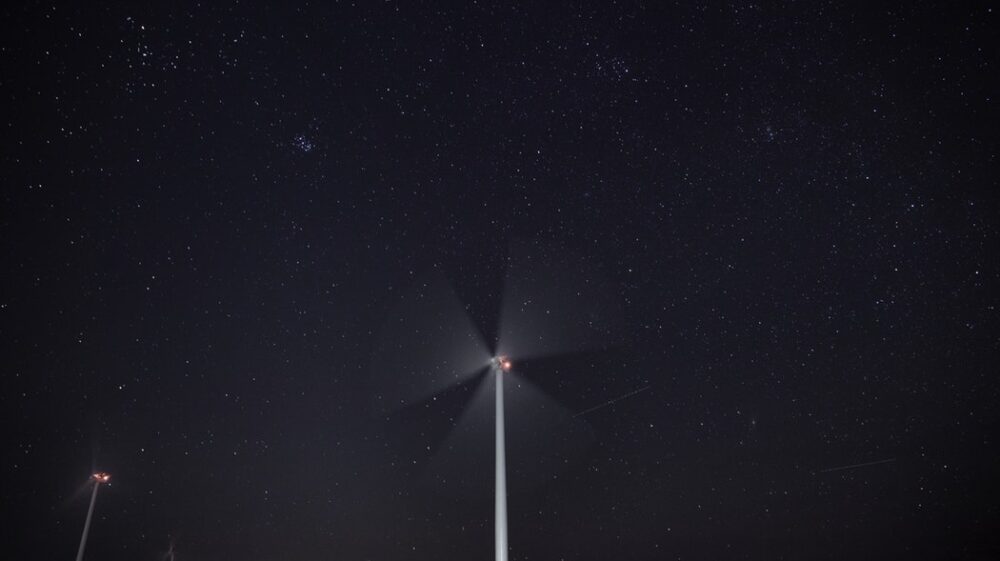 Windmills by night under star filled sky