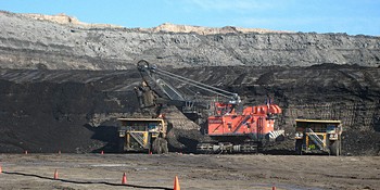 Trucks wait in position and are loaded by shovel with oil sands in Fort McMurray, Alberta.