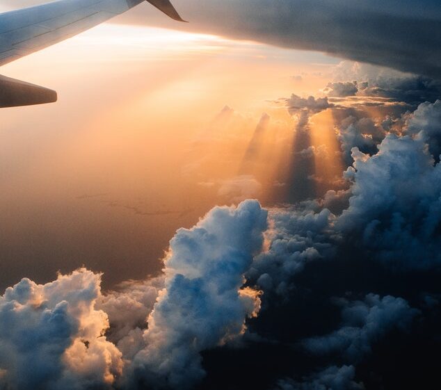 View from airplane in sunset; orange clouds and sun