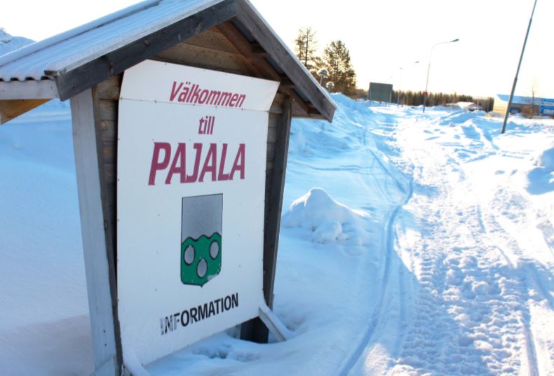 A Welcome to Pajala sign in Swedish in a winter landscape
