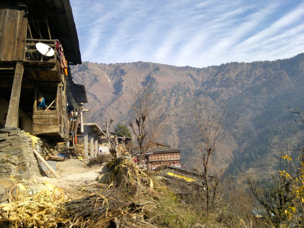 A wooden home on a hill, with mountains spanning in the distance