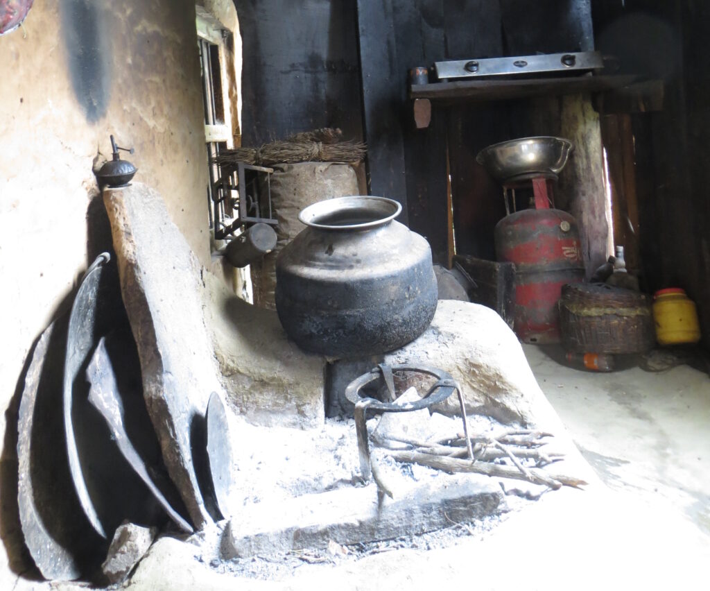 A typical Himachali kitchen, with a woodburning “tripod” stove in the foreground and an LPG stove with a gas cylinder in the back