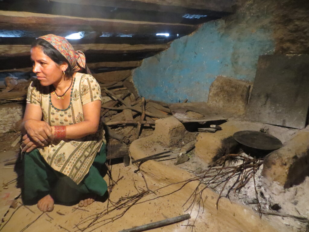 A woman sitting in a kitchen with an open cookstove