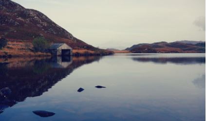 Lake with a shed in front of a big mountain