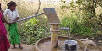 A girl using a public water handpump