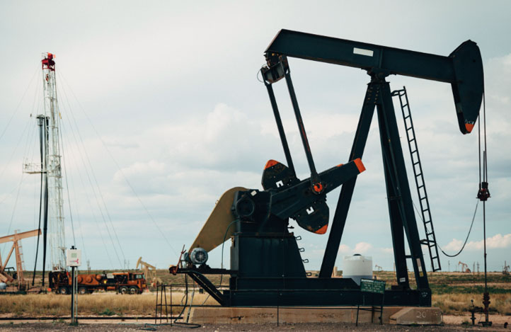 A black oil pump extracting oil from the ground, with some beige-coloured pumps in the background.