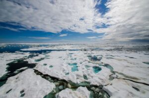 Arctic landscape with clear skies overhead and cracked ice on the water