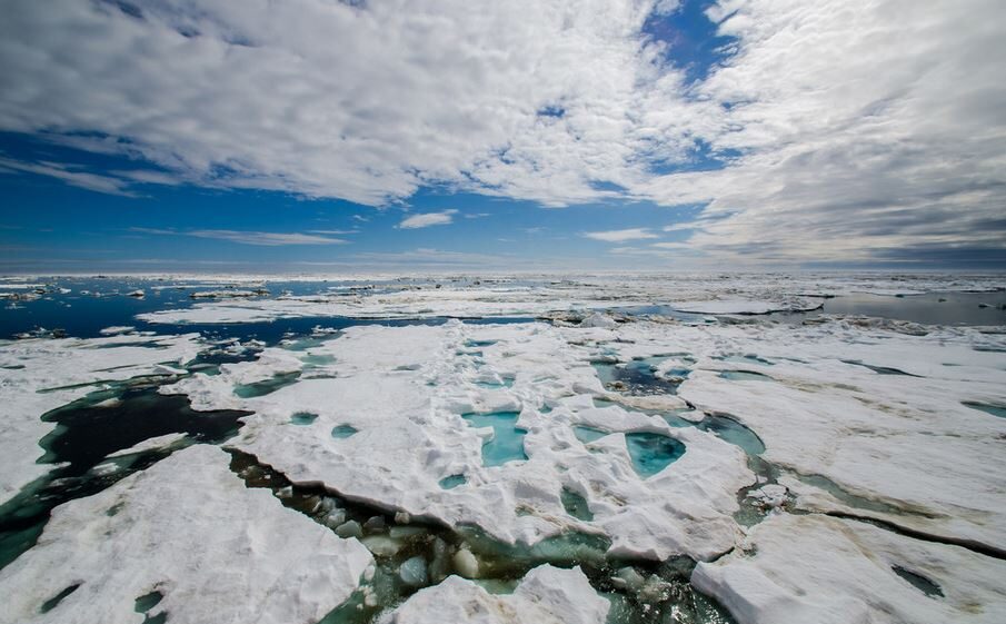 Arctic landscape with clear skies overhead and cracked ice on the water