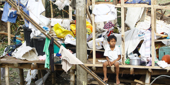 A boy in front of damaged home