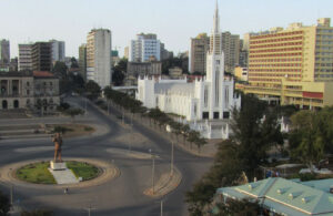 A statue stands at the centre of a city square in front of buildings in a mix of architecture styles.