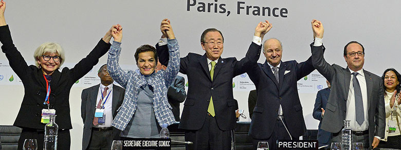 A group of negotiators holding their hands up in triumph at the Paris Climate Change Conference, November 2015.