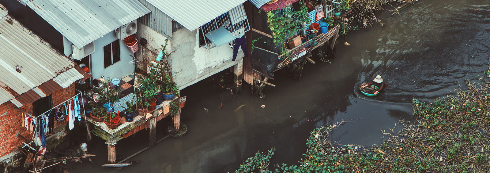 A person wading down a river next to houses