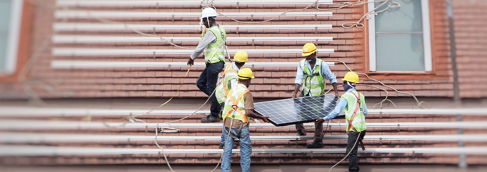 Workers installing solar panels on a roof