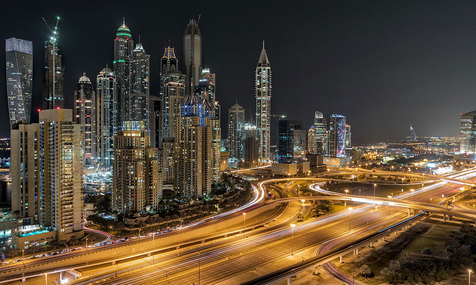 A bustling night view of Dubai's skyscrapers and roads.