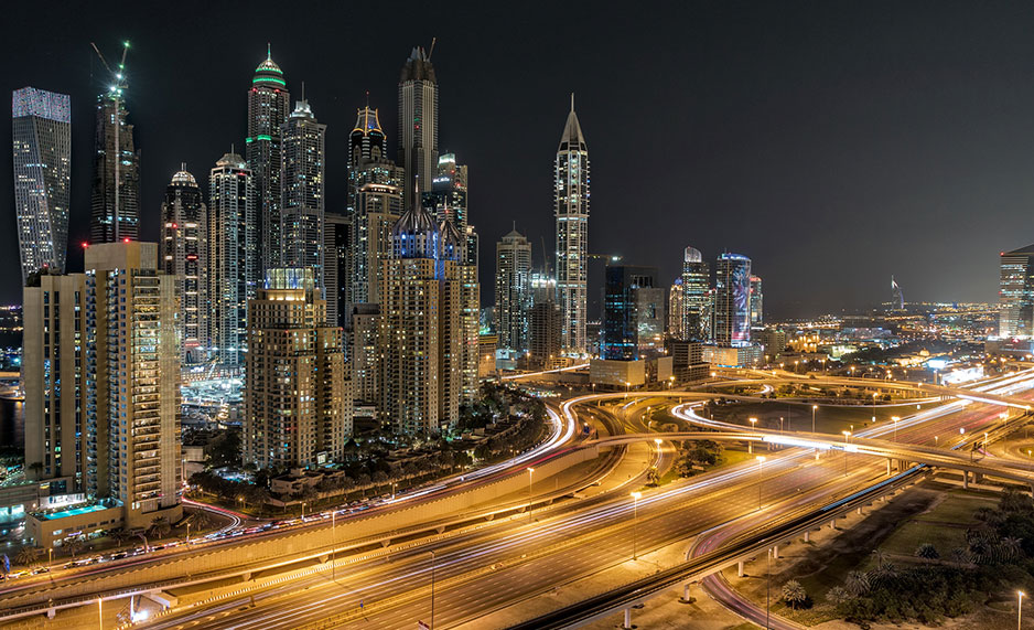 A bustling night view of Dubai's skyscrapers and roads.