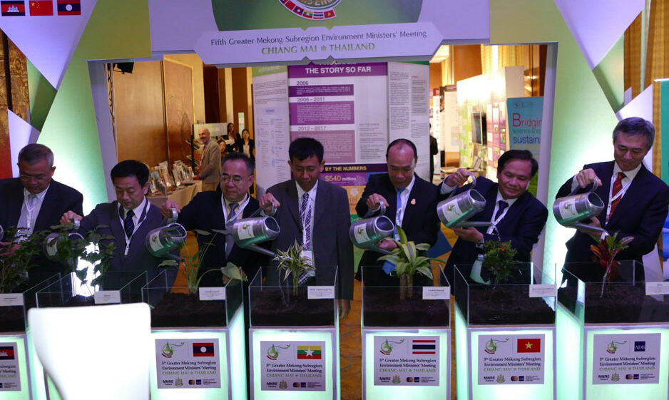 A row of men wearing suits watering plants at an event.