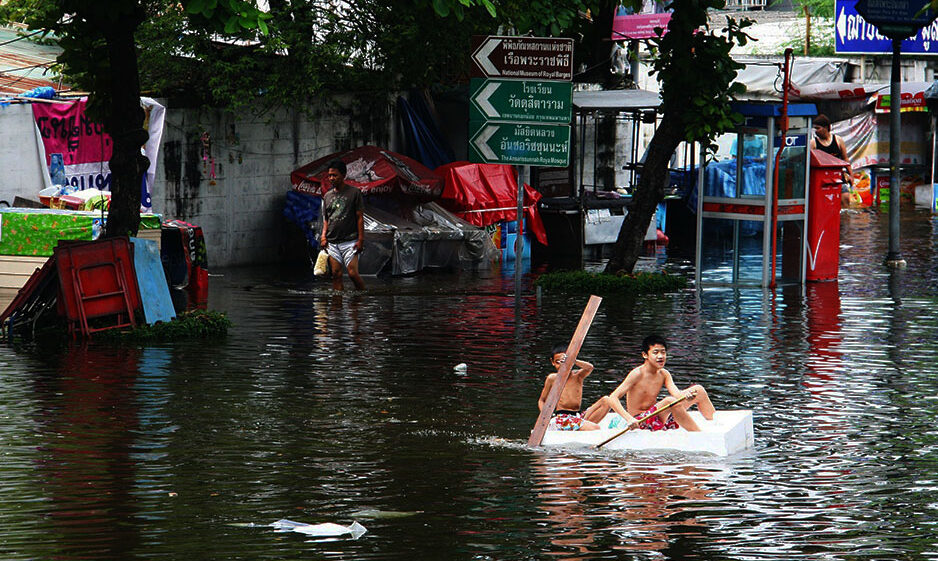 Boys rowing in a flooded urban area in Thailand