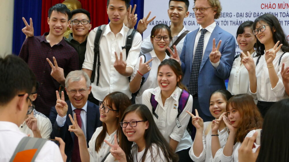 A group of students standing happily with Ambassador Högberg