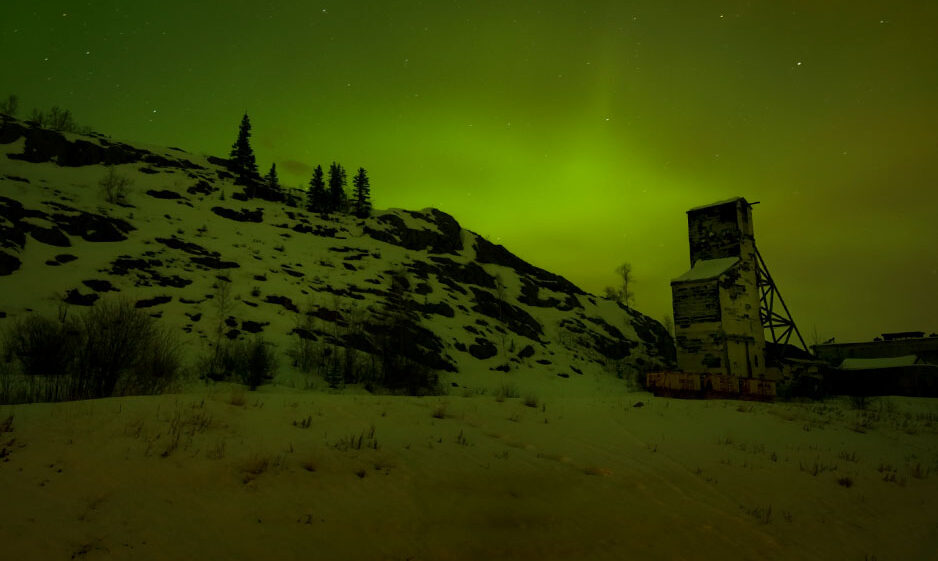 Eerie aurora light green a snowy landscape with a mineshaft