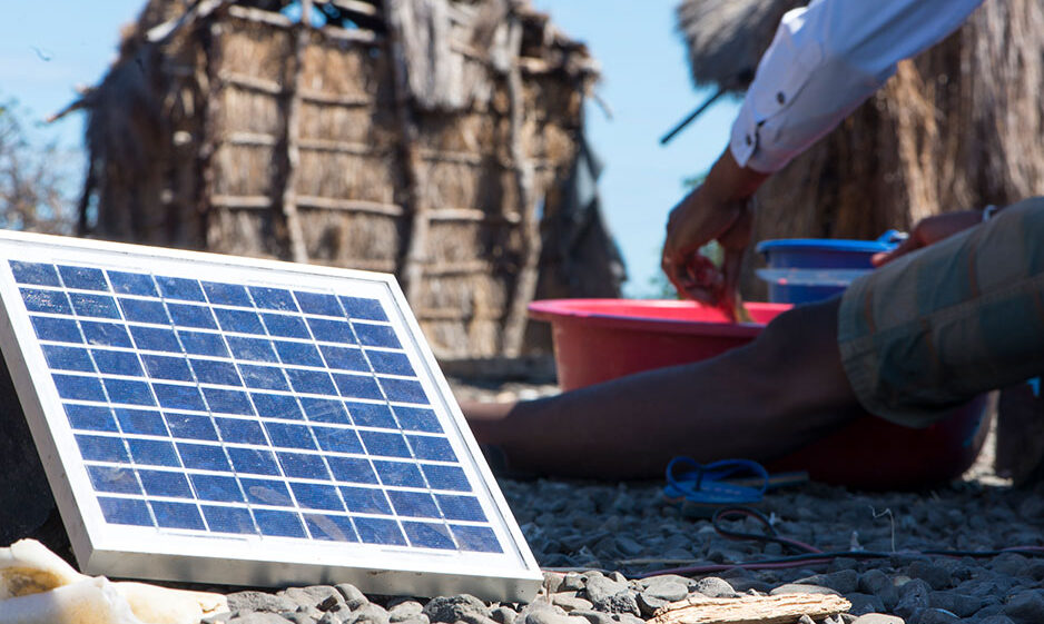 A person sitting next to a small solar panel.