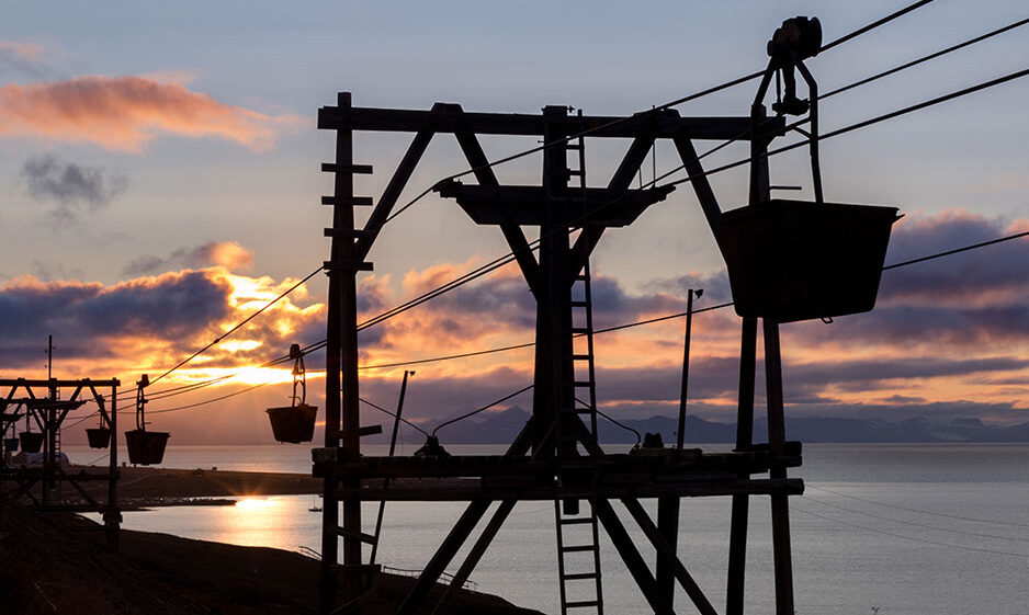Silhouette of the old cableway for transporting coal from mines in Longyearbyen, Svalbard. Midnight sun scenery with light clouds and mountains in background.