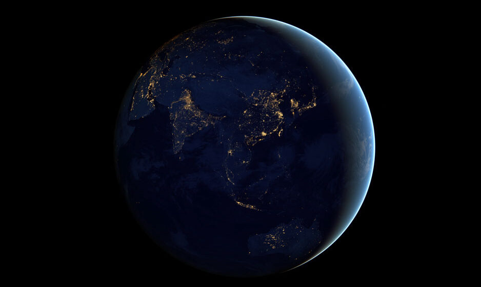 Photo of Earth as seen from space, with city lights illuminating an otherwise dark side of our planet.