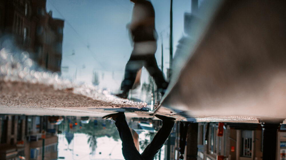 Man walking over puddle in city