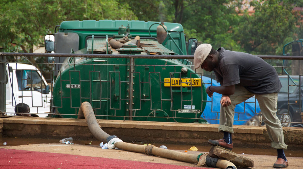 man attends to sewage collection truck and pipe