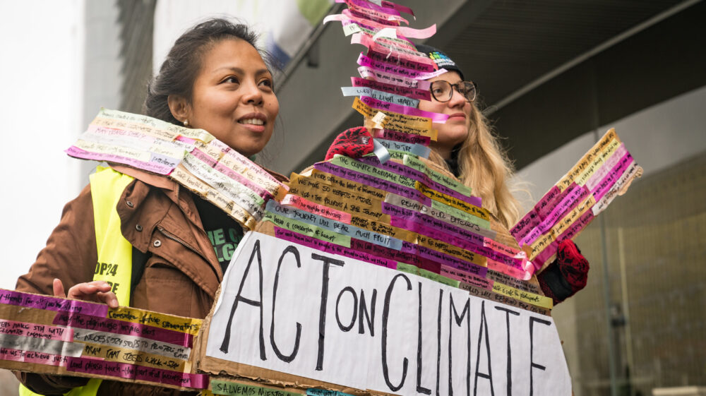 Two participants in the Climate Pilgrimage, carrying prayer ribbons with prayers written on them.