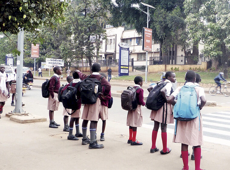 Photo of schoolchildren waiting to cross a busy road in Kampala -Alon Mwesigwa