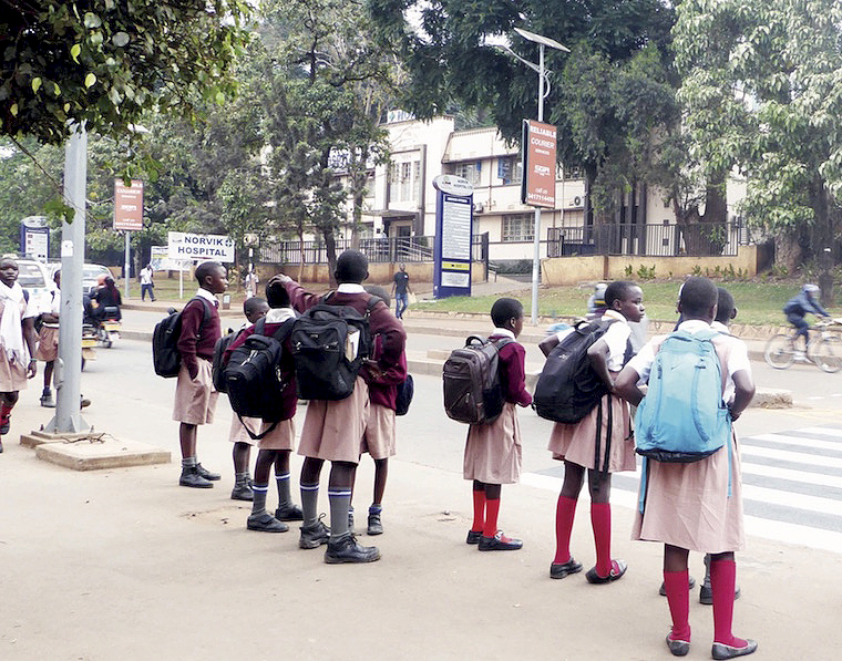 Photo of schoolchildren waiting to cross a busy road in Kampala -Alon Mwesigwa