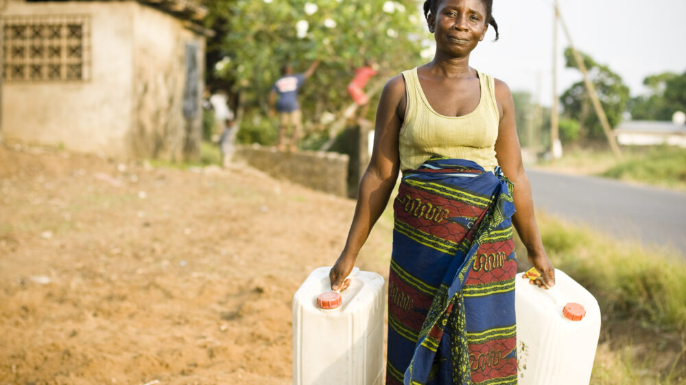 African woman carrying two water jugs.