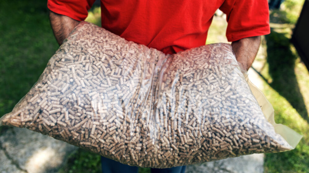 Man carrying transparent sack of wood pellets in hands