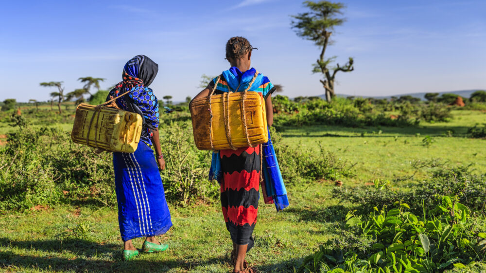 Girls carrying water in plastic containers in Nigeria