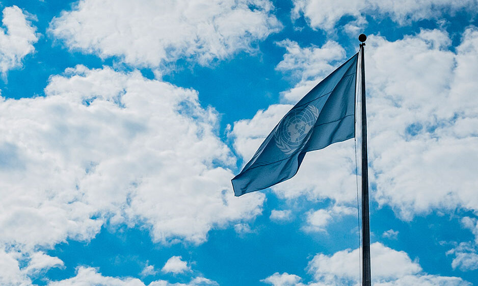 United Nations flag against a bright, cloudy sky