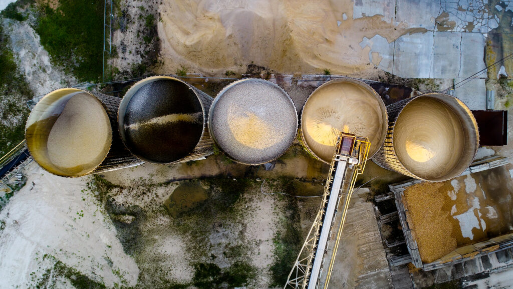 Aerial top-down view of large silos containing materials at a cement factory.