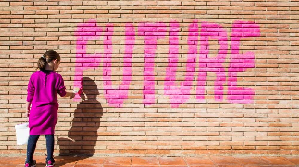Little girl painting the word future on a wall as an act of protest for future generations.