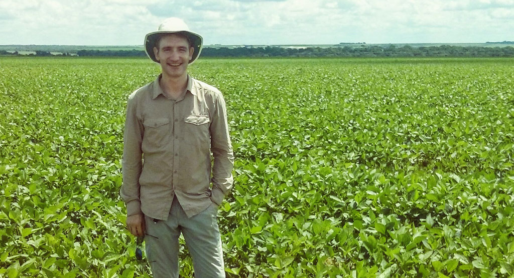 Michael Lathuillière standing in a sunny crop field in Brazil.