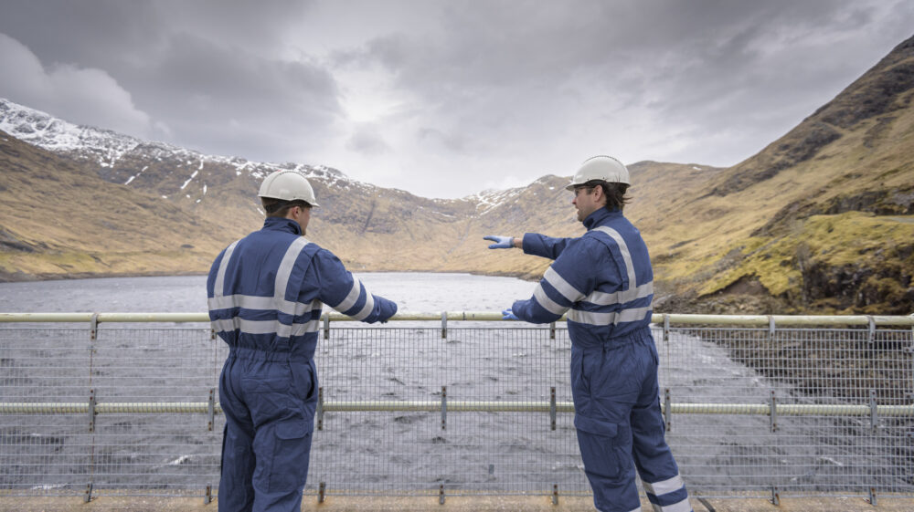 Workers on dam with water at hydroelectric power station