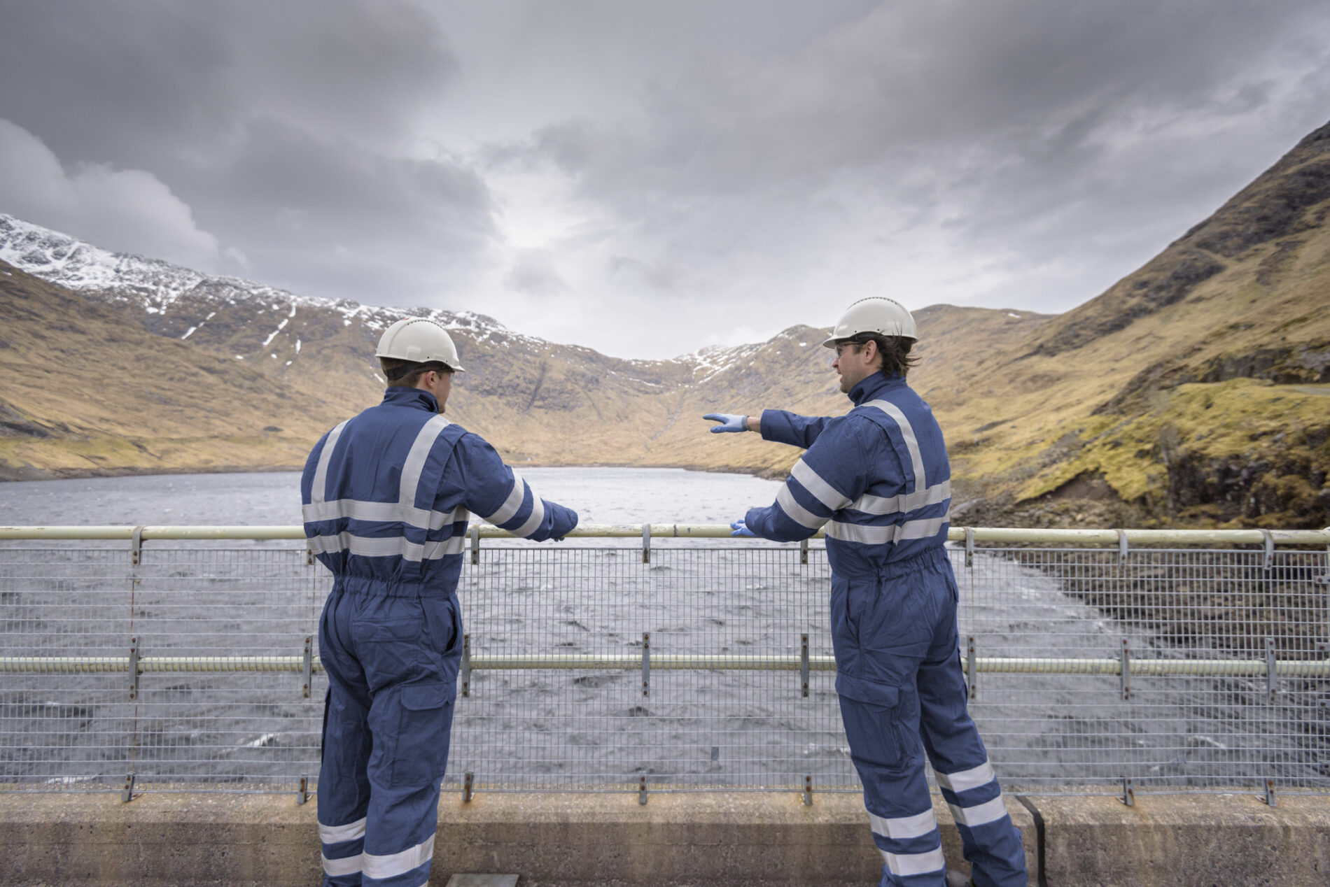 Workers on dam with water at hydroelectric power station