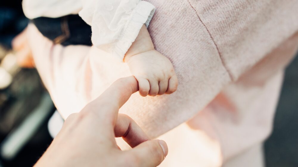 Close up of baby's hand holding an adult's finger