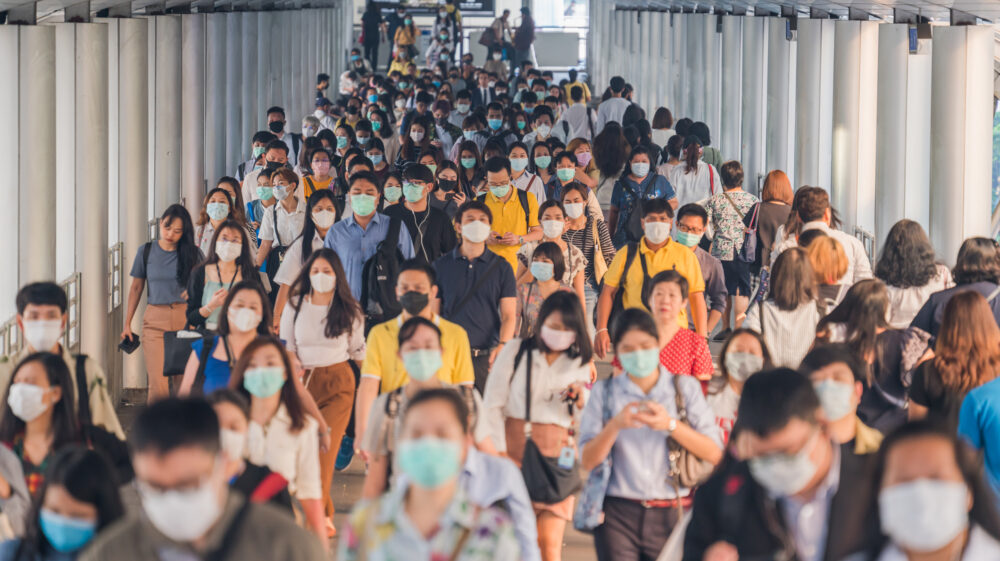 Crowd of commuters wearing face masks in Bangkok during morning rush hour