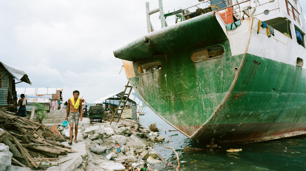 Man walking near grounded ship post storm surge