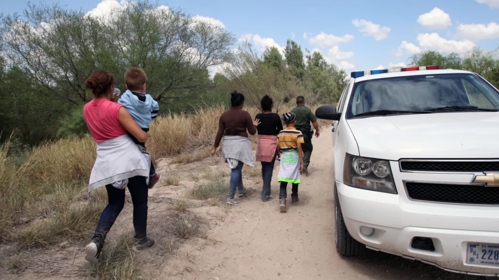 A group of migrants walking along a dusty road in Texas, USA.