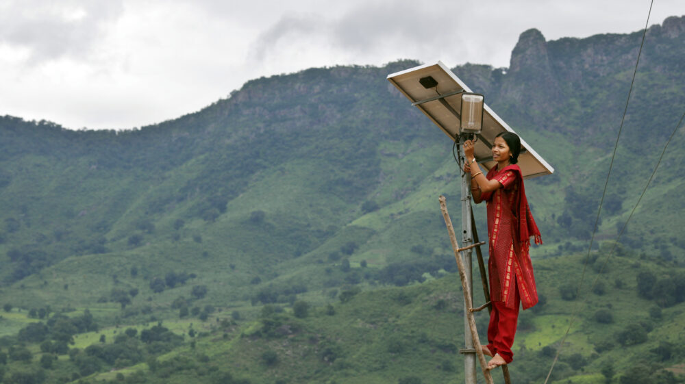 A solar engineer conducts maintenance on a solar panel in the solar-powered village of Tinginapu, India.