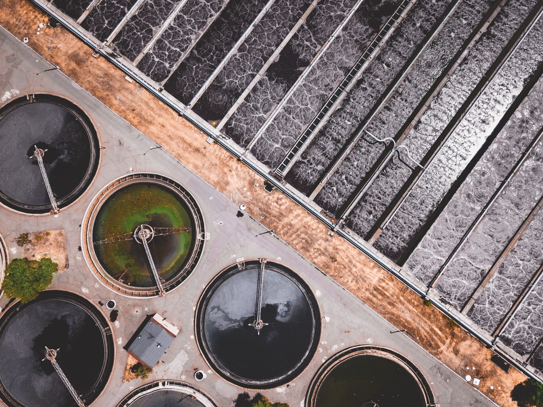 Aerial view of circular tanks and rectangular basins at a wastewater treatment facility.