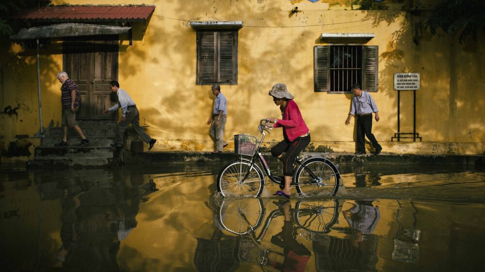 A woman cycles through floods in Vietnam