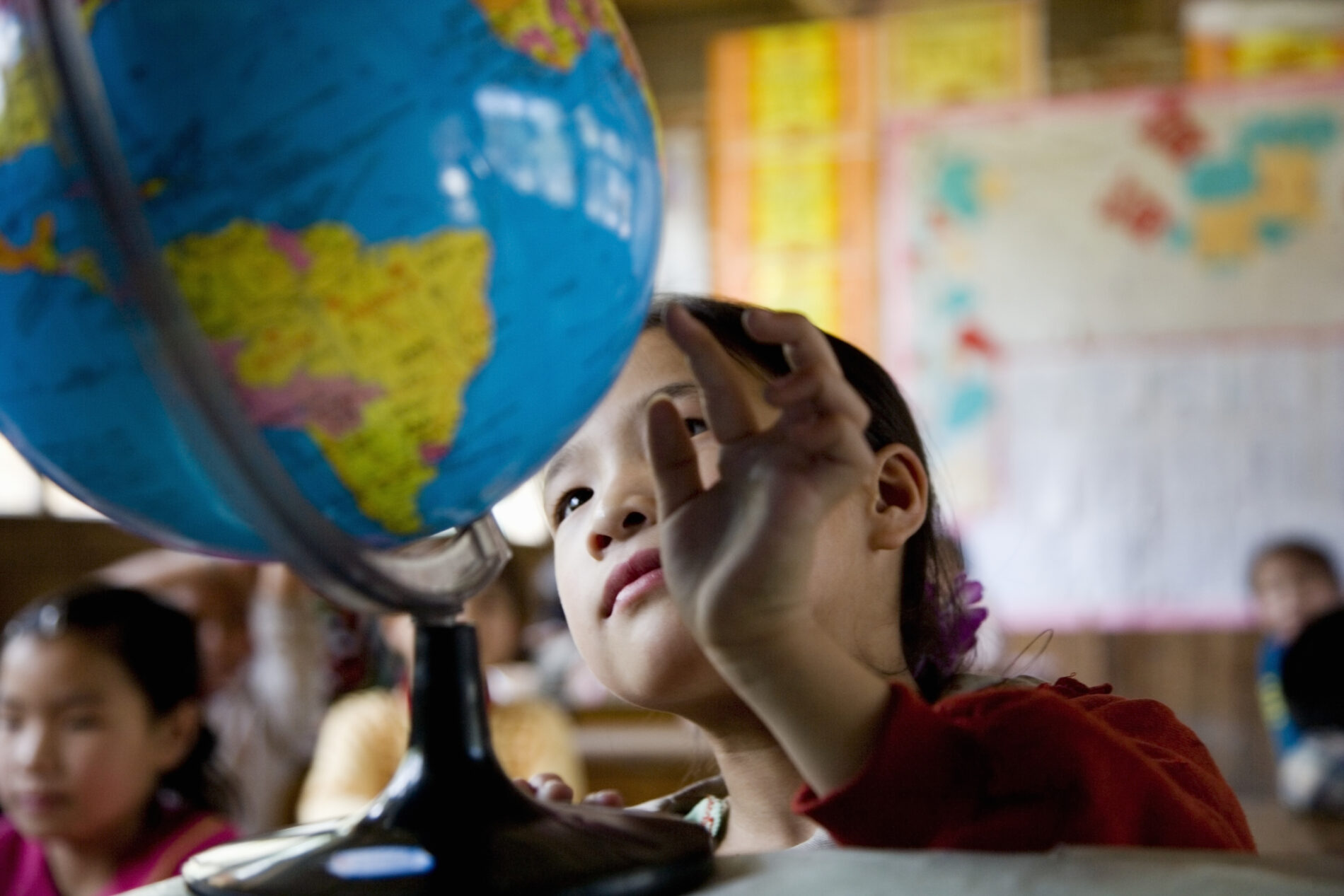 Girl in primary school looking at the globe, Guangxi Province, China.