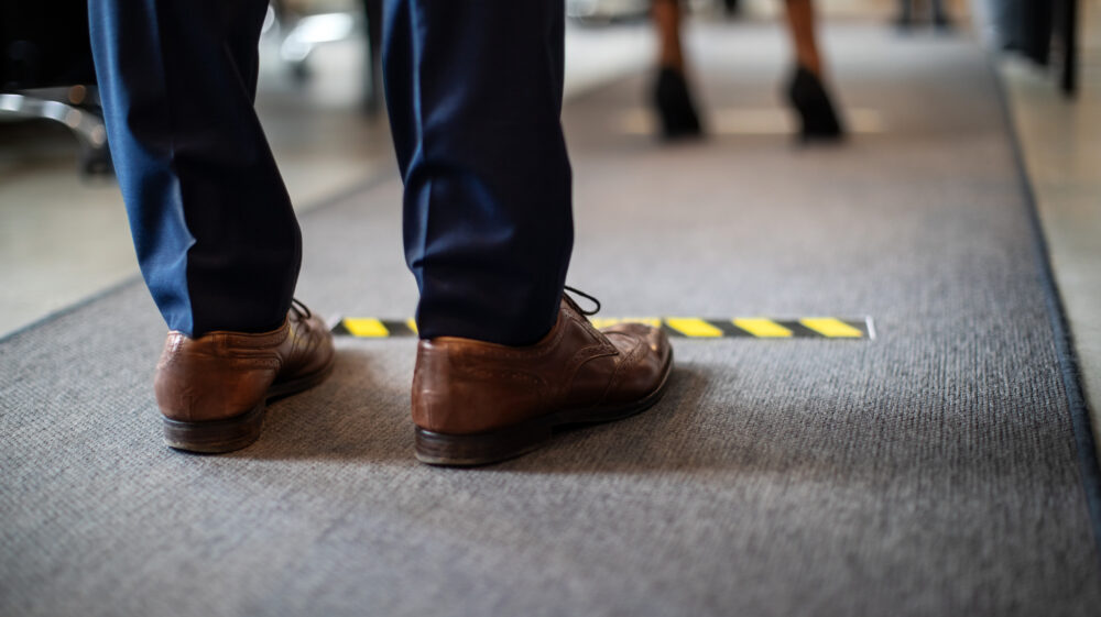 Man in queue with socially distanced markings on floor, Berlin, Germany