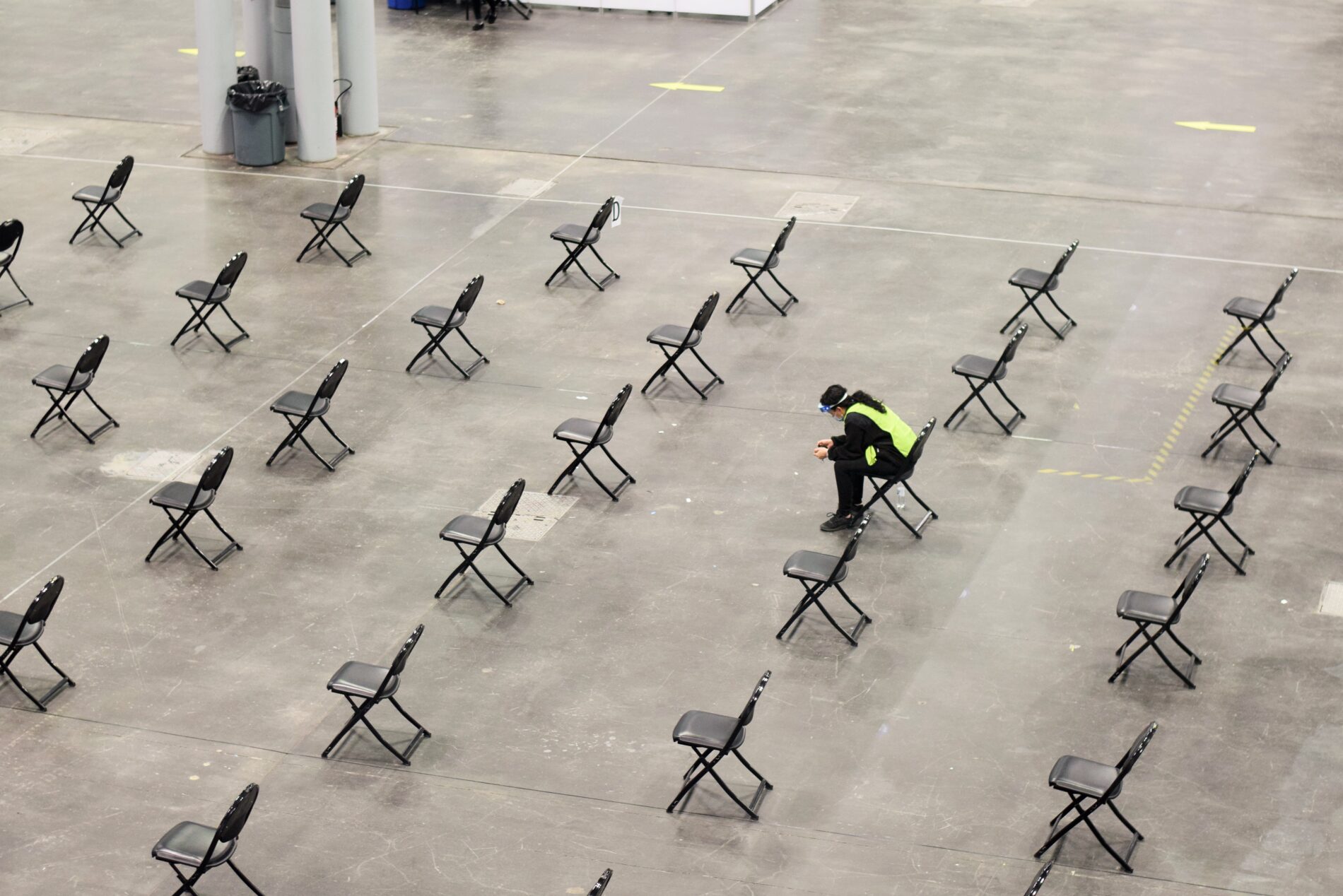 Worker sits on chair in empty vaccination centre
